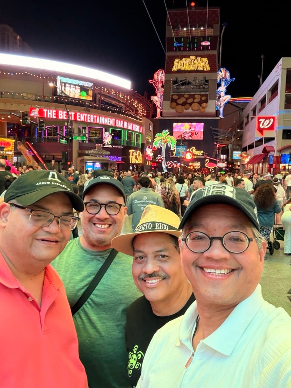 Close-up Fremont Street selfie with neon lights exploding behind the four friends
