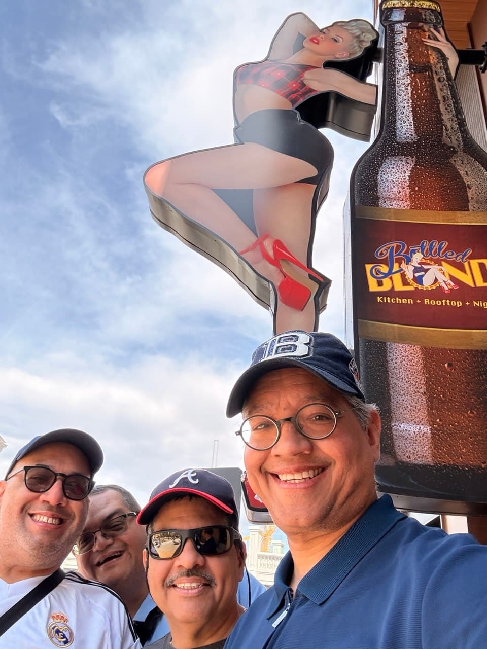 The four friends under the Bottled Blonde sign on the Strip